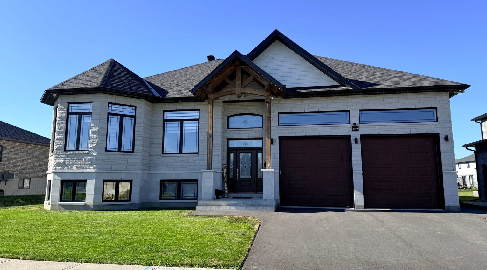 Front of our signature custom home: stone raised bungalow with timber-frame porch and double garage